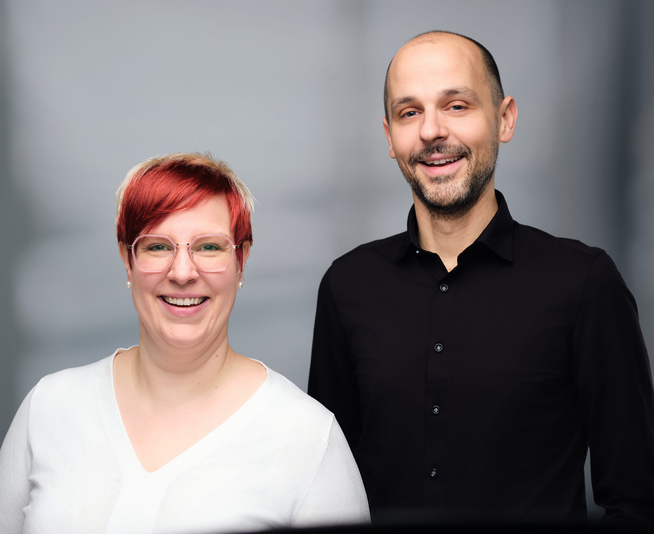 Zwei Menschen lächeln in die Kamera.