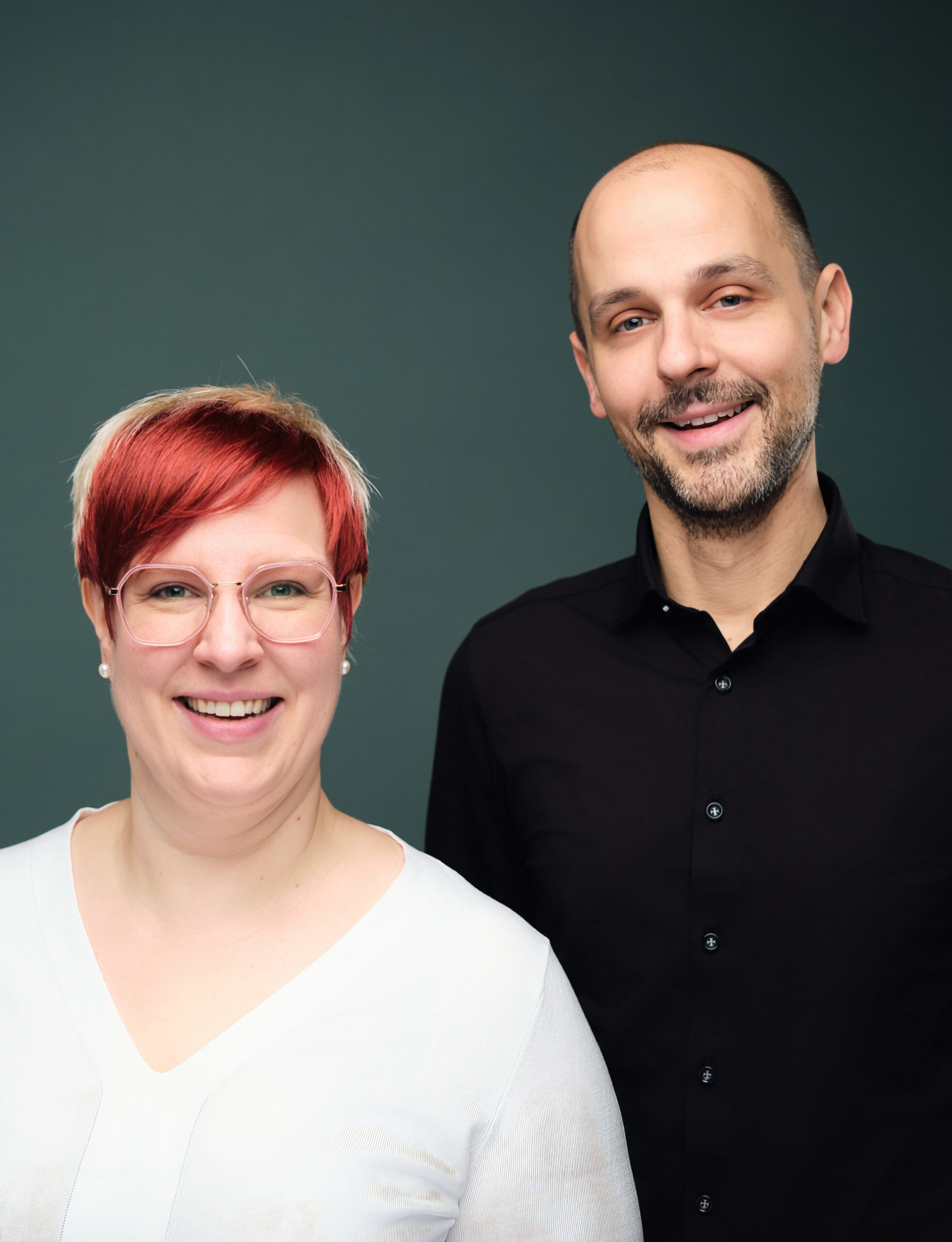 Zwei Menschen lächeln in die Kamera.