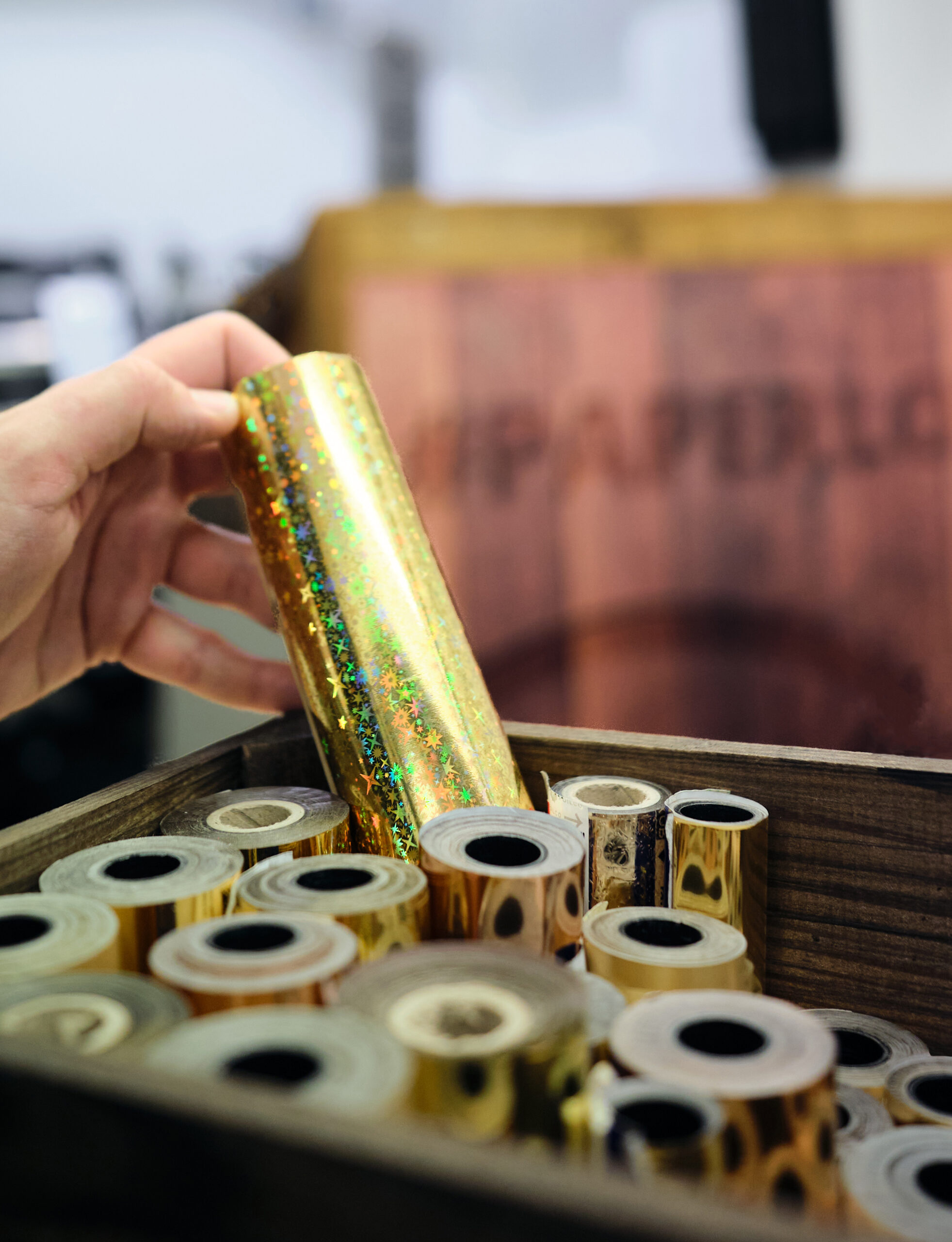 Eine Hand hält eine goldene Heißfolienprägeform in der Hand.