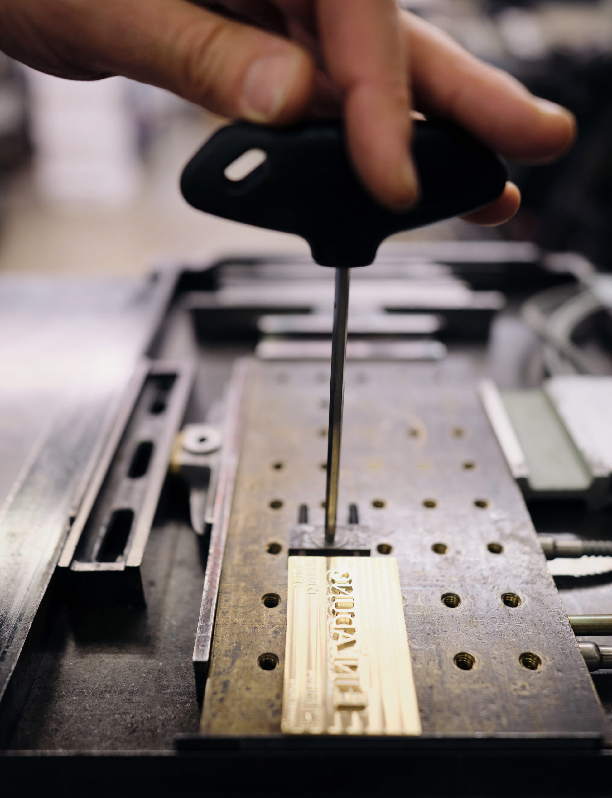 Eine Hand hält eine goldene Heißfolienprägeform in der Hand.